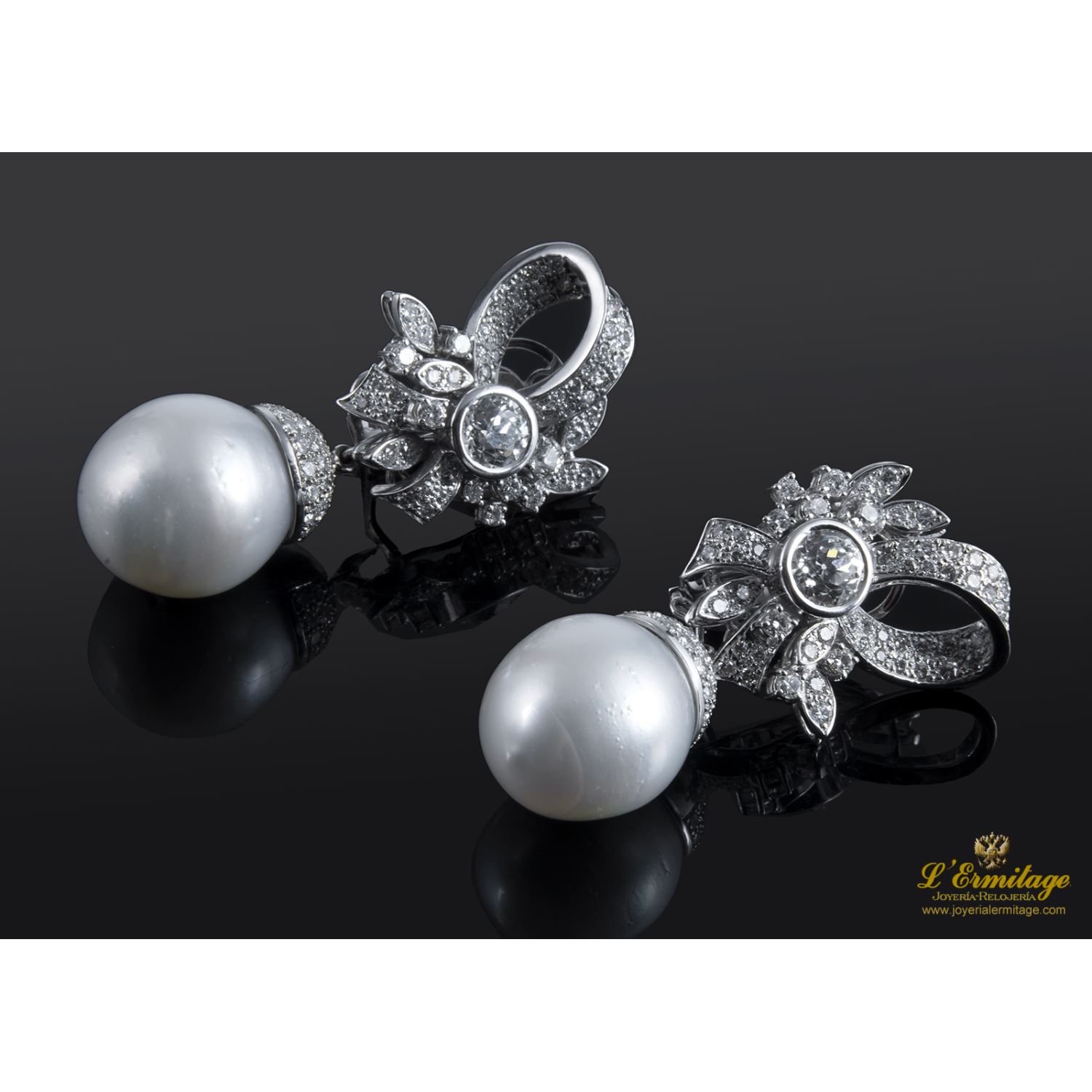 Pendientes desmontables en forma de lazo realizados en oro blanco. Presenta perlas australianas y brillantes.
